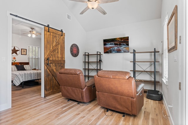 sitting room featuring ceiling fan, a barn door, vaulted ceiling, and light wood-style flooring