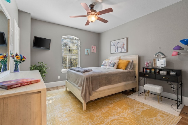 bedroom featuring wood finished floors, a ceiling fan, and baseboards