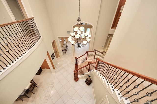 2256 Lake Cove Way, Seabrook, TX 77586 - stairway featuring a chandelier, a towering ceiling, tile patterned flooring, and arched walkways