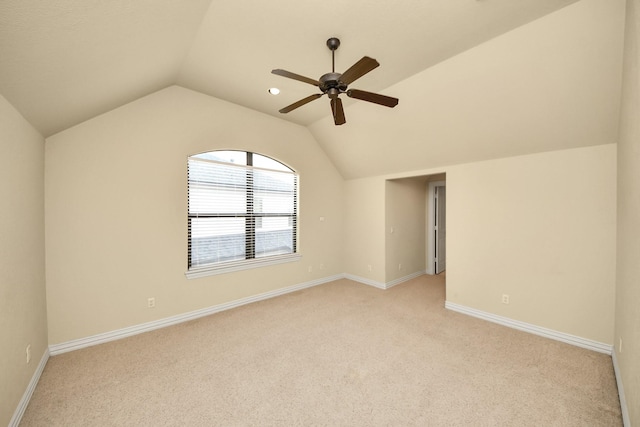 empty room with lofted ceiling, ceiling fan, light carpet, and baseboards