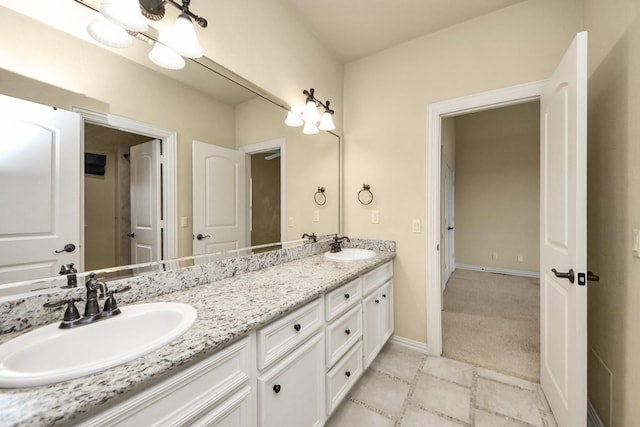 bathroom featuring double vanity, baseboards, and a sink