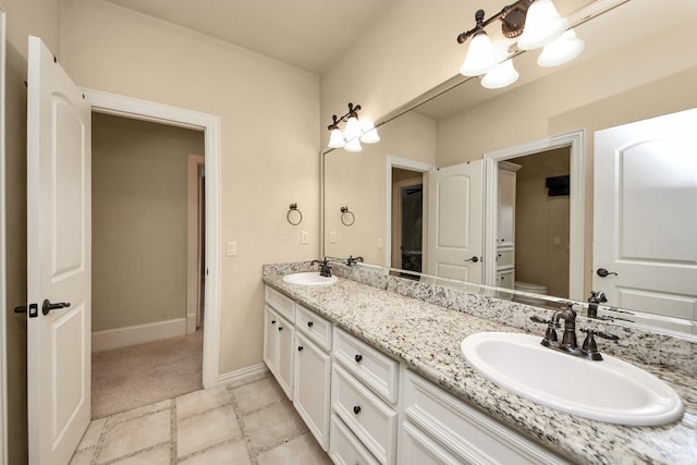 full bathroom with double vanity, a sink, toilet, and baseboards