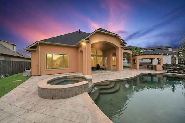 rear view of house featuring a patio, fence, a pool with connected hot tub, and stucco siding