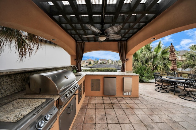 view of patio featuring area for grilling, ceiling fan, exterior kitchen, and outdoor dining space