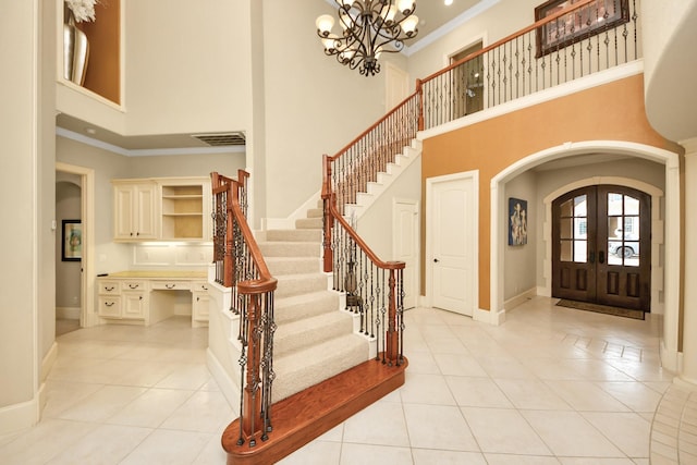 foyer entrance with arched walkways, light tile patterned floors, visible vents, ornamental molding, and baseboards