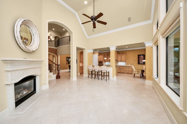 living area with high vaulted ceiling, decorative columns, ornamental molding, and a glass covered fireplace