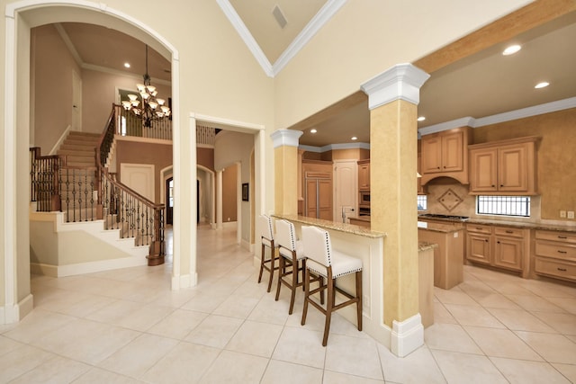 kitchen with light tile patterned floors, arched walkways, light stone counters, a towering ceiling, and a kitchen breakfast bar