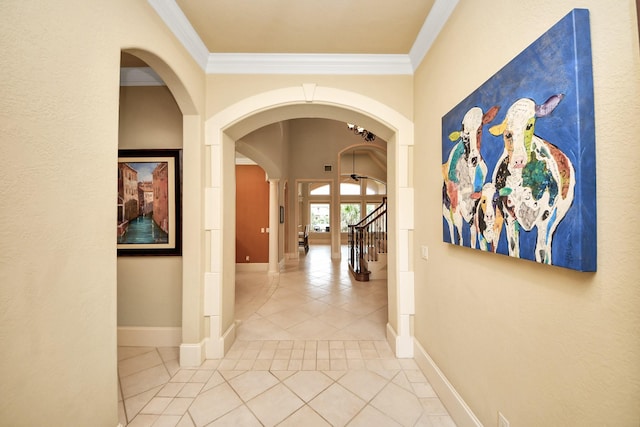 hallway with arched walkways, ornamental molding, and baseboards