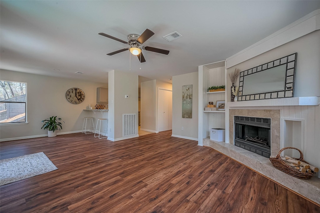 32 Sawmill Grove Ln, The Woodlands, TX 77380 - unfurnished living room with a tiled fireplace, visible vents, baseboards, and wood finished floors