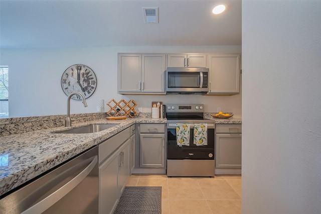 kitchen featuring light tile patterned floors, visible vents, gray cabinets, a sink, and stainless steel appliances