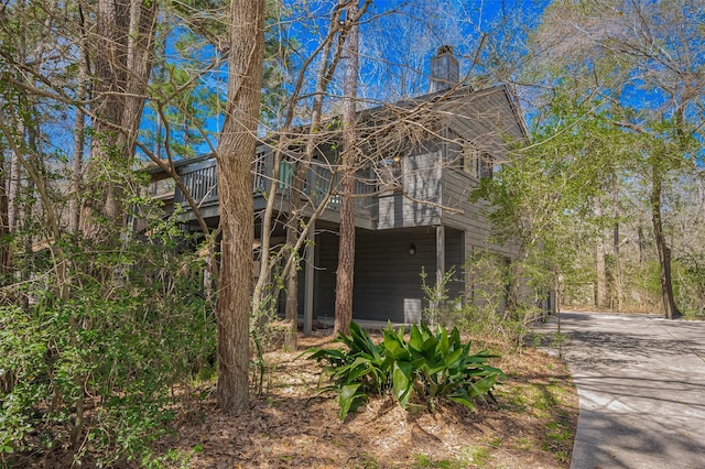 view of property exterior with concrete driveway and a chimney