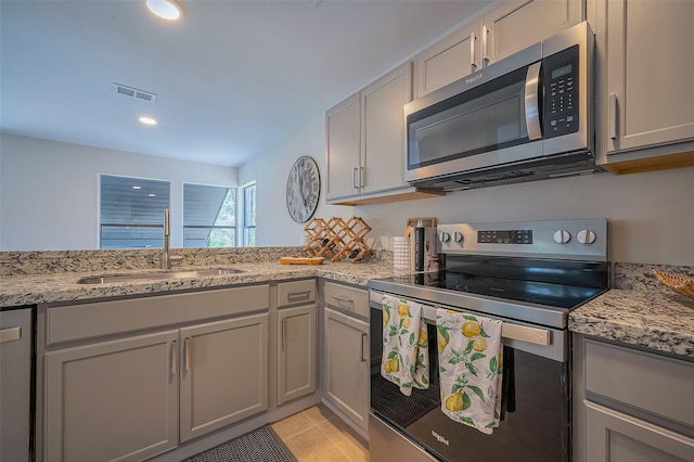 kitchen featuring visible vents, gray cabinetry, stainless steel appliances, and a sink