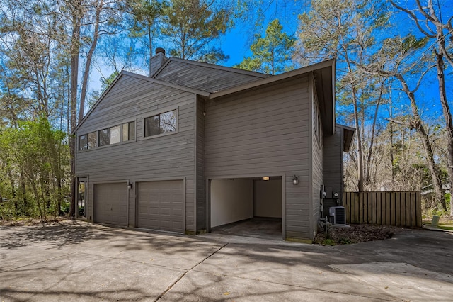 view of home's exterior featuring driveway, a chimney, and a garage