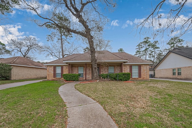 view of front facade with brick siding, a tile roof, and a front yard