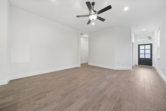 unfurnished living room with ceiling fan, recessed lighting, wood finished floors, and baseboards