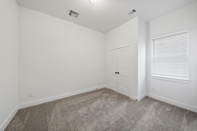 carpeted spare room with visible vents and baseboards