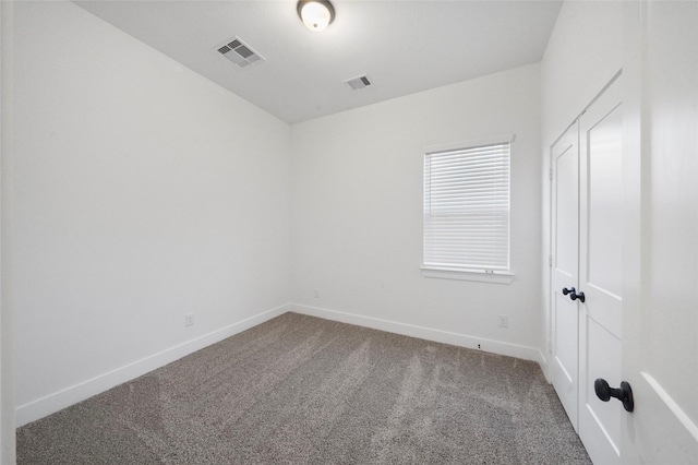 carpeted spare room featuring visible vents and baseboards