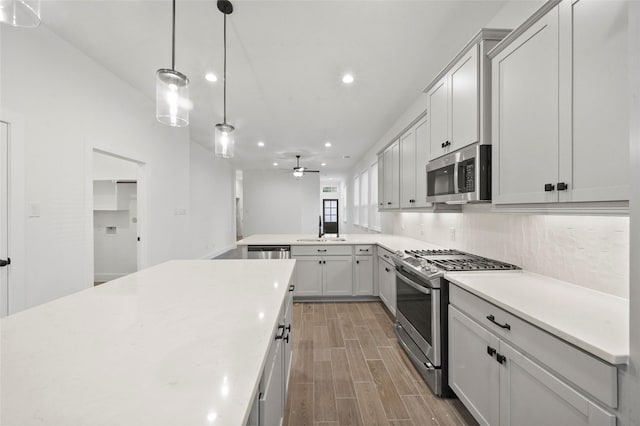 kitchen featuring appliances with stainless steel finishes, light countertops, a sink, and decorative light fixtures