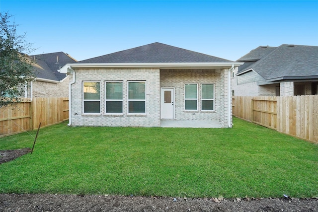 back of property featuring a yard, a fenced backyard, and brick siding