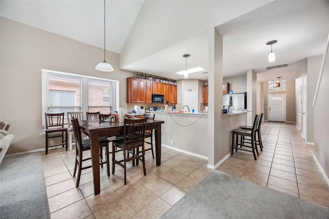 dining space featuring high vaulted ceiling, light tile patterned flooring, visible vents, and baseboards