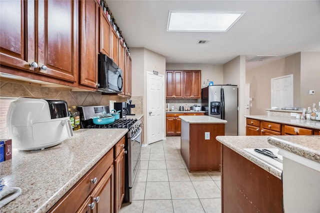 kitchen with light tile patterned floors, visible vents, a kitchen island, brown cabinets, and stainless steel appliances