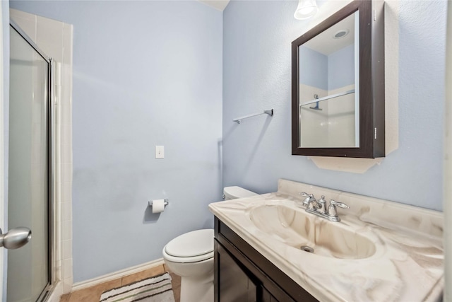 bathroom featuring toilet, a shower with door, baseboards, and vanity