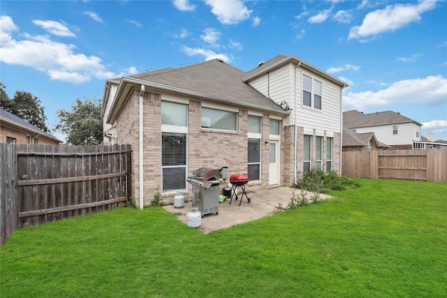 rear view of property featuring a yard, a patio area, brick siding, and a fenced backyard