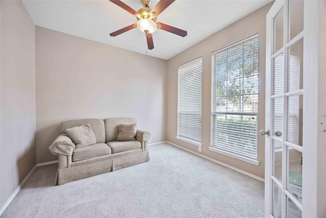 sitting room featuring light carpet, baseboards, a ceiling fan, and french doors