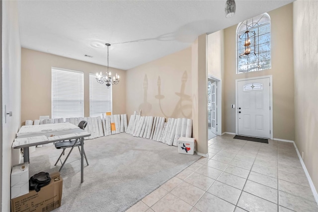 entrance foyer with light carpet, a notable chandelier, baseboards, and light tile patterned floors