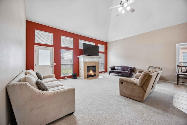 carpeted living room with ceiling fan, high vaulted ceiling, a tile fireplace, and baseboards