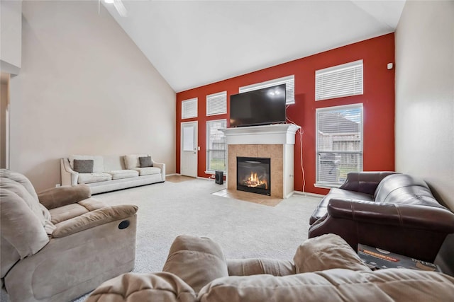 living area with high vaulted ceiling, light carpet, and a tiled fireplace