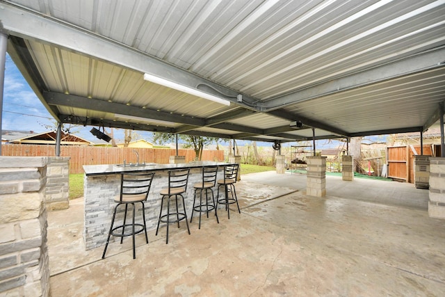 view of patio featuring outdoor dry bar, a fenced backyard, and a sink