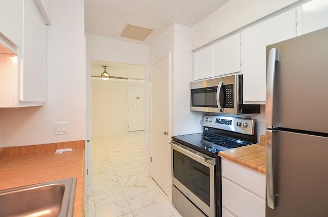 kitchen with white cabinets, marble finish floor, stainless steel appliances, light countertops, and a sink