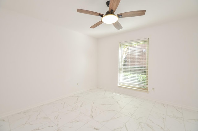 spare room featuring marble finish floor, ceiling fan, and baseboards