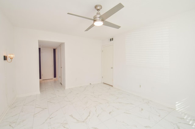 unfurnished room with marble finish floor, a ceiling fan, visible vents, and baseboards