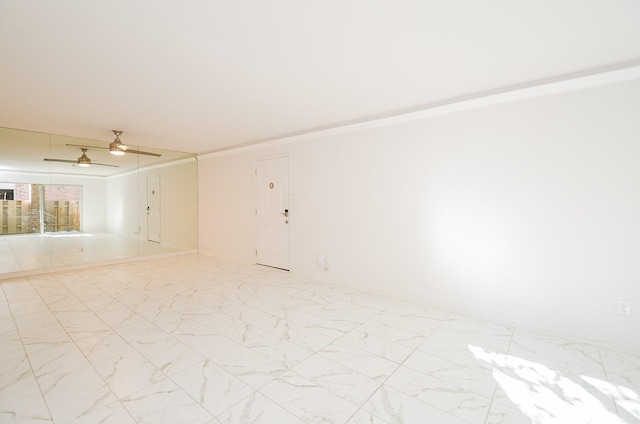 unfurnished room featuring ceiling fan, marble finish floor, and ornamental molding