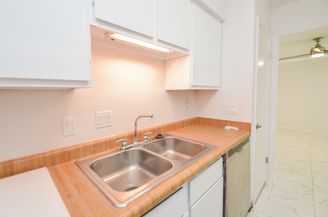 kitchen featuring marble finish floor, a sink, white cabinetry, and dishwashing machine