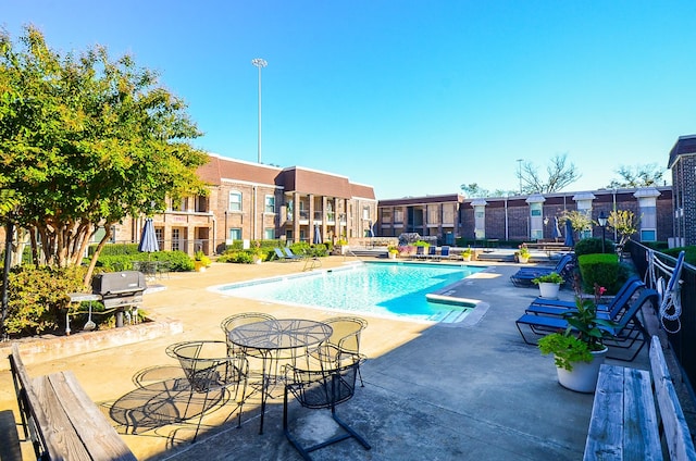 community pool with a patio area and a grill