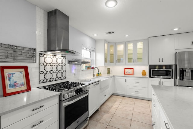 kitchen with visible vents, white cabinets, appliances with stainless steel finishes, wall chimney range hood, and glass insert cabinets