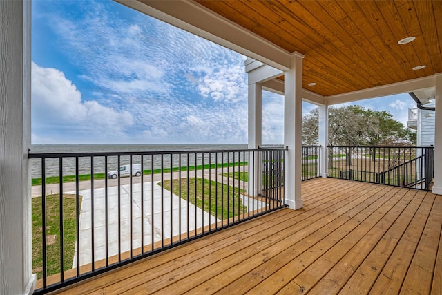 wooden terrace featuring a beach view and a water view