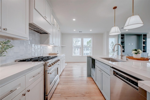 kitchen featuring hanging light fixtures, appliances with stainless steel finishes, a sink, and white cabinets