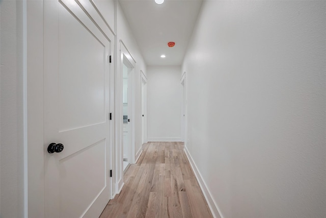 hall featuring light wood-type flooring, baseboards, and recessed lighting