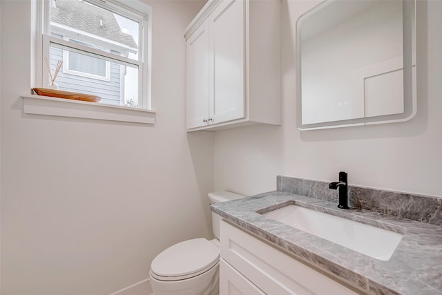 bathroom featuring baseboards, vanity, and toilet