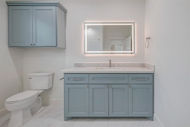 bathroom with toilet, marble finish floor, vanity, and baseboards