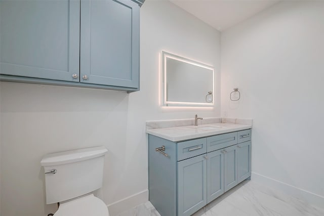 bathroom with toilet, marble finish floor, vanity, and baseboards