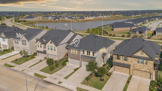 aerial view at dusk featuring a residential view and a water view