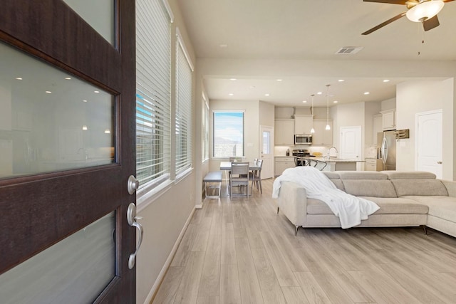 living room featuring recessed lighting, a ceiling fan, baseboards, visible vents, and light wood-style floors