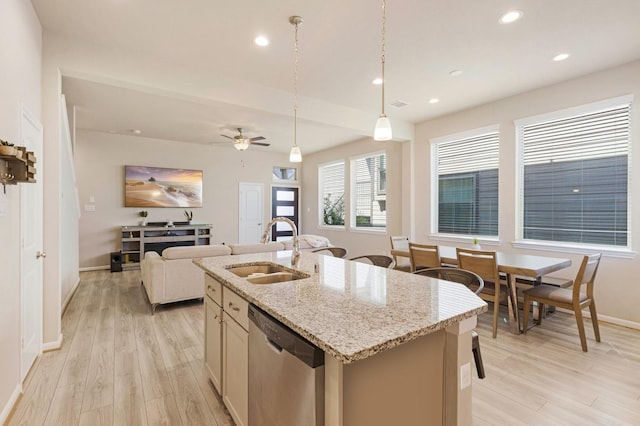 kitchen with light stone counters, a kitchen island with sink, open floor plan, dishwasher, and pendant lighting