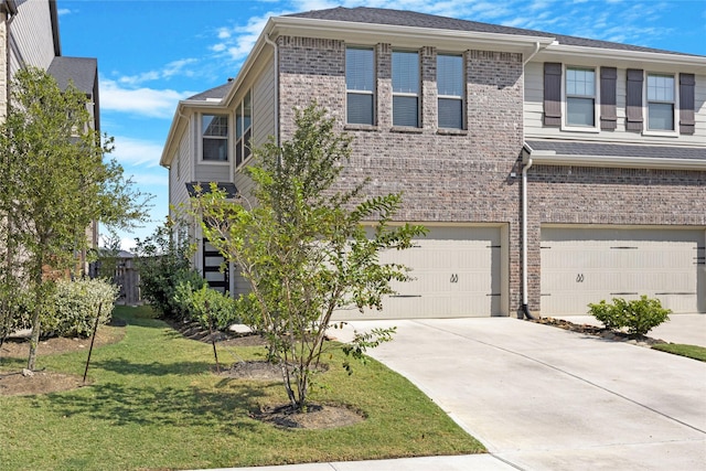 view of front facade featuring a garage, driveway, brick siding, and a front yard