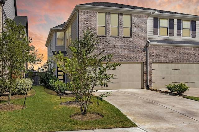 view of front facade with a garage, concrete driveway, brick siding, and a yard